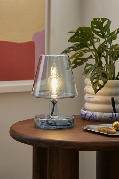 a lamp sitting on top of a wooden table next to a potted plant in a vase