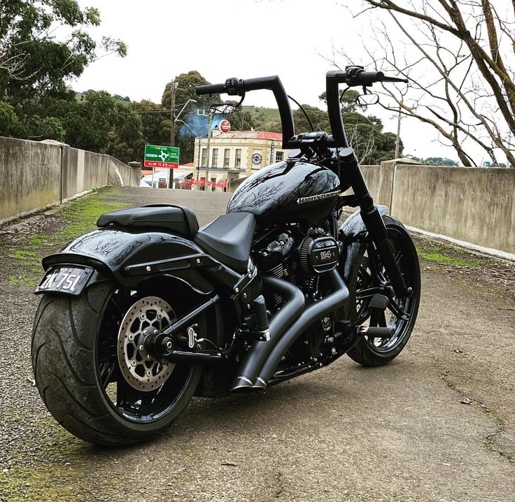 a black motorcycle parked on the side of a road next to a fence and trees