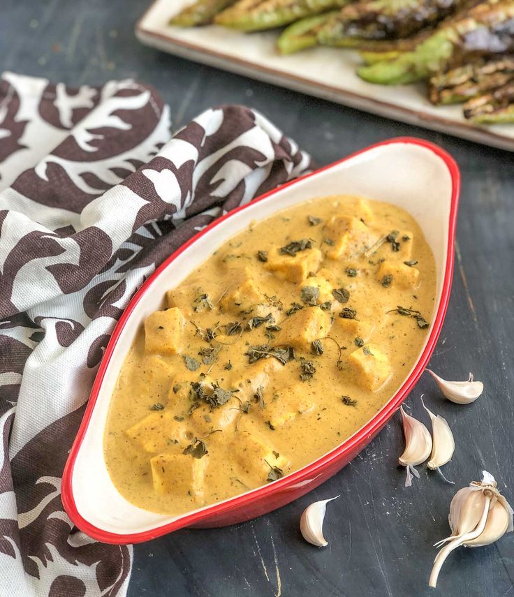 a red bowl filled with yellow sauce next to asparagus and other food items