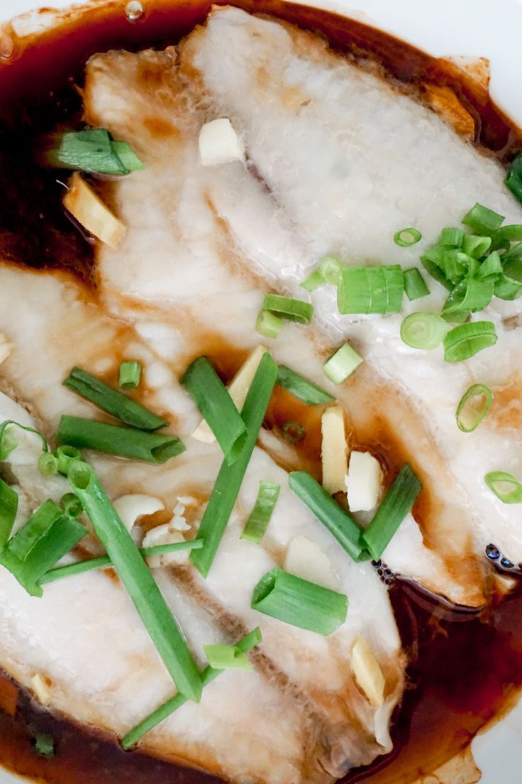 a white plate topped with meat covered in sauce and green onions