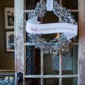 a door with a wreath hanging from it's side and a sign that says, what does cold outside?