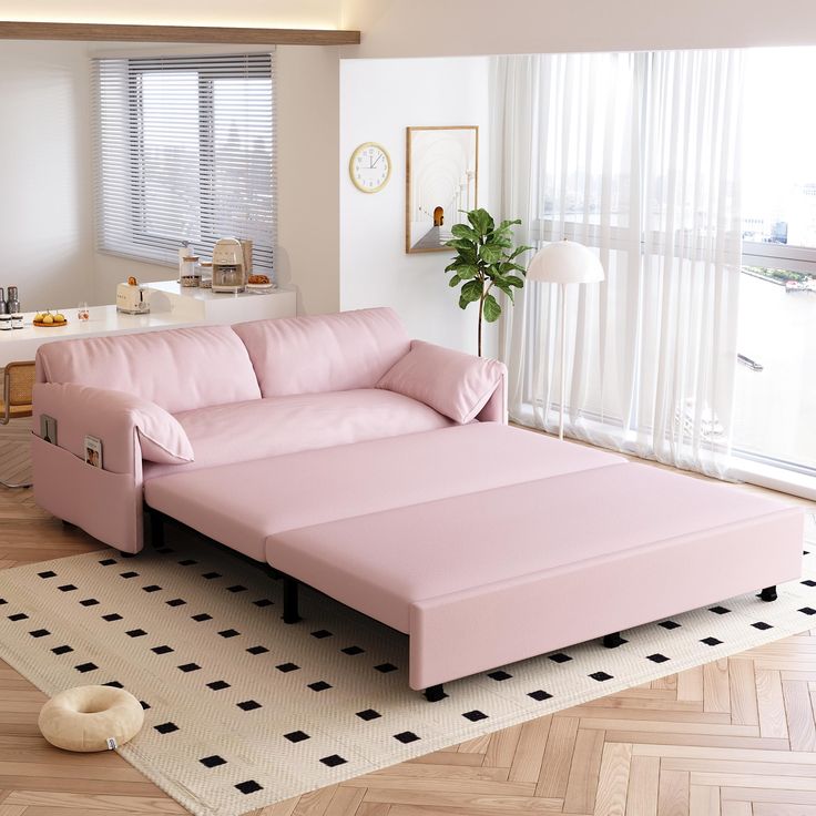 a pink couch sitting on top of a hard wood floor next to a large window