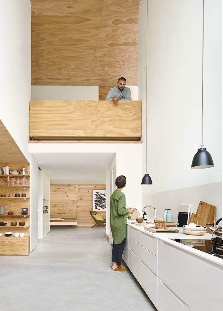 a woman standing in a kitchen next to a wooden shelf filled with dishes and bowls