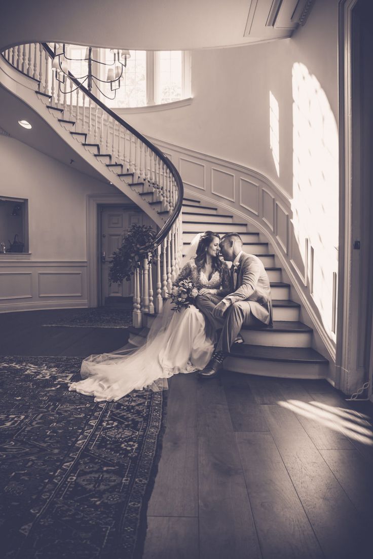 a bride and groom are sitting on the stairs at their wedding reception in black and white