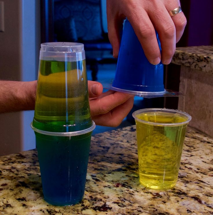 a person is pouring colored liquid into cups