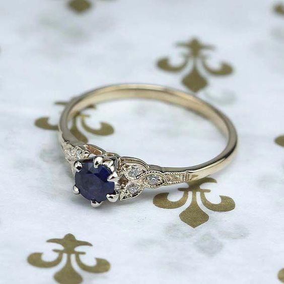 an engagement ring with a blue sapphire and diamond accents on a white background covered in gold florets