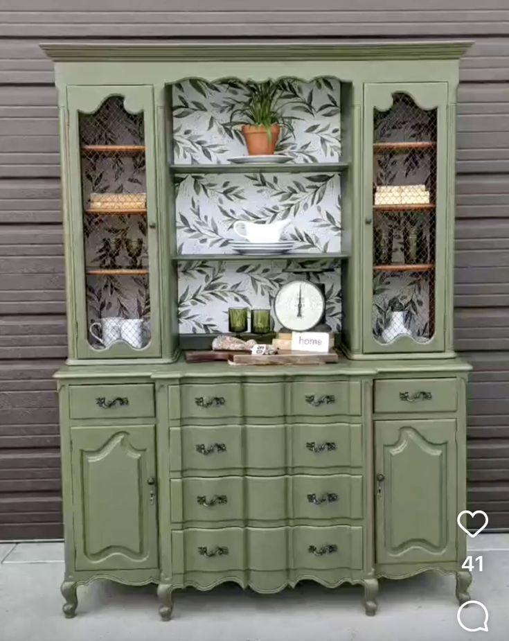 a green china cabinet with glass doors and drawers