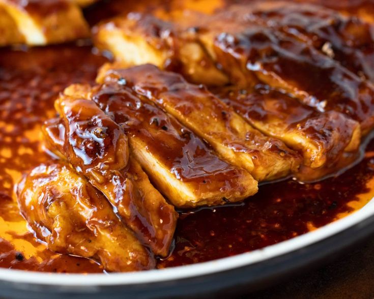 some meat is being cooked in sauce on top of another dish with chopsticks