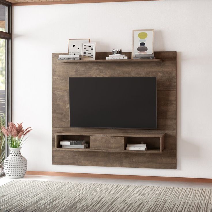 a living room with a large tv mounted on the wall and a vase filled with flowers