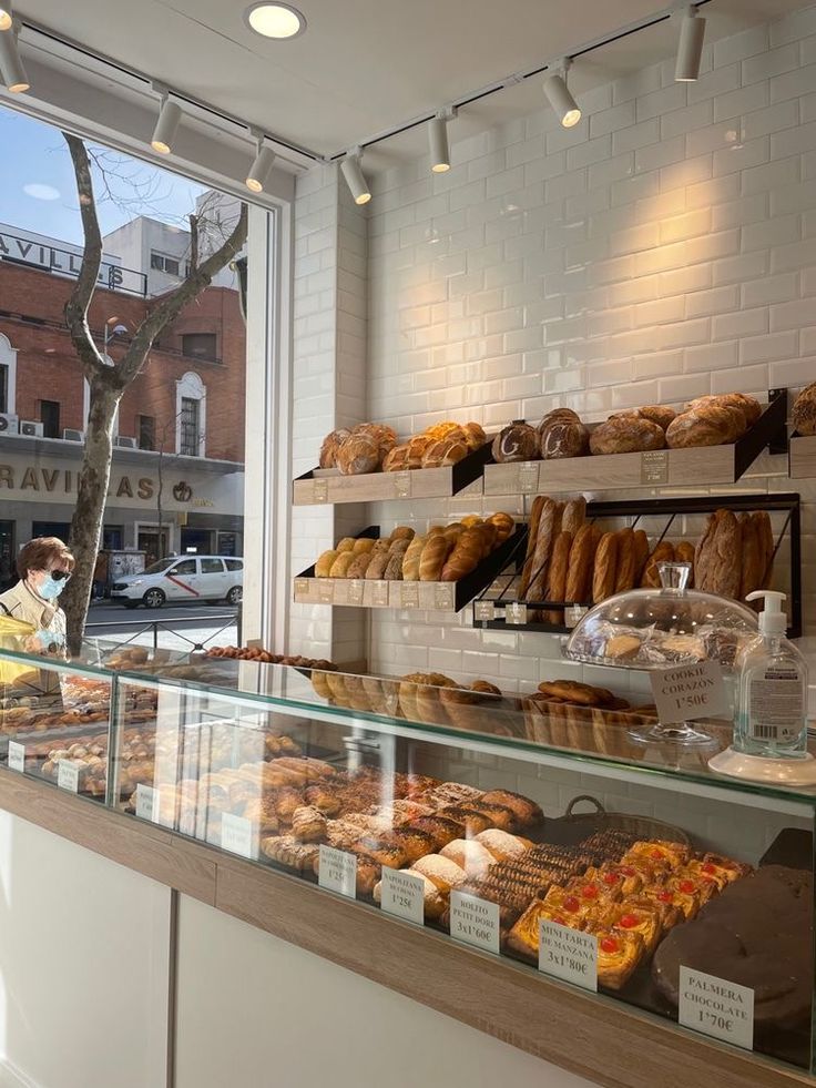 a bakery filled with lots of donuts and pastries next to a large window