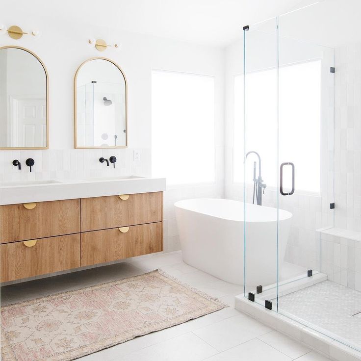 a bathroom with two sinks, a bathtub and a large mirror on the wall