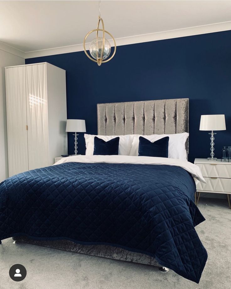 a bedroom with blue walls, white furniture and a chandelier hanging from the ceiling