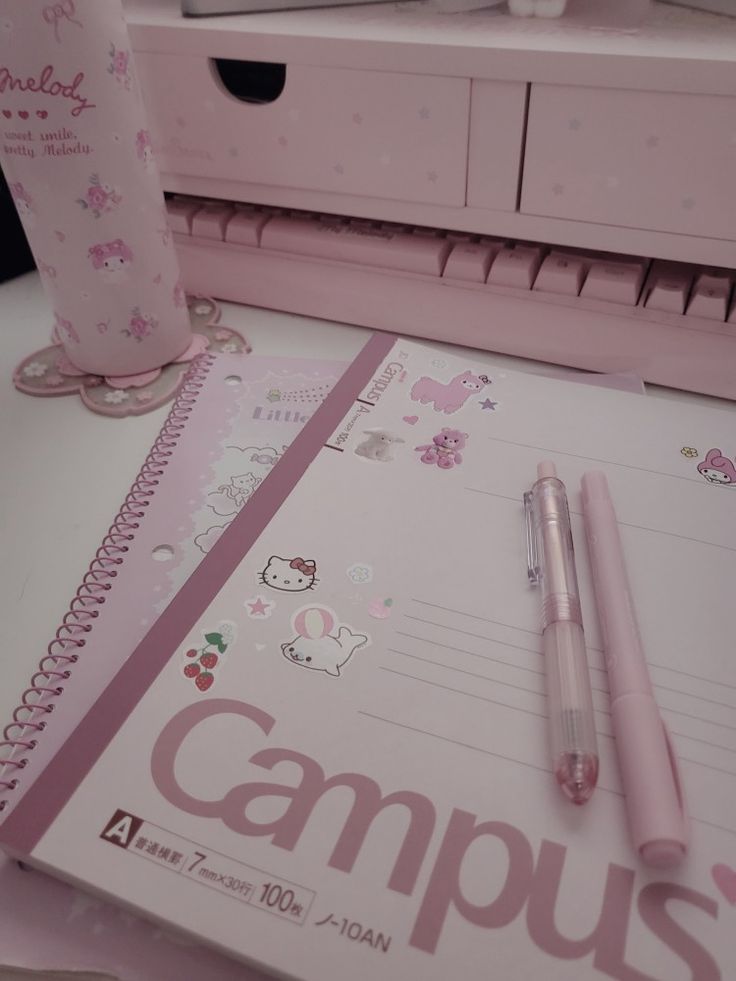 a pink notebook and pen sitting on top of a desk