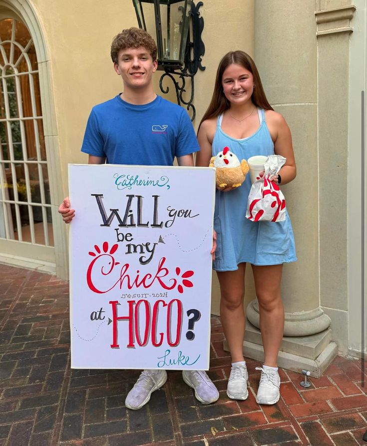 two people standing next to each other holding up a sign that says will you be my chick at hoo?