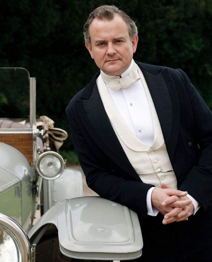 a man in a tuxedo standing next to a car