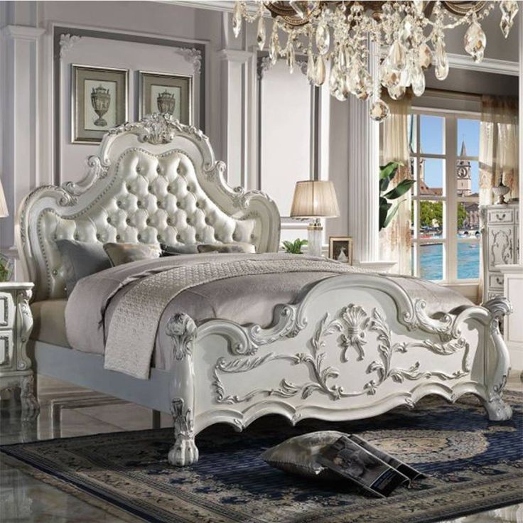 a white bed sitting in a bedroom next to a chandelier