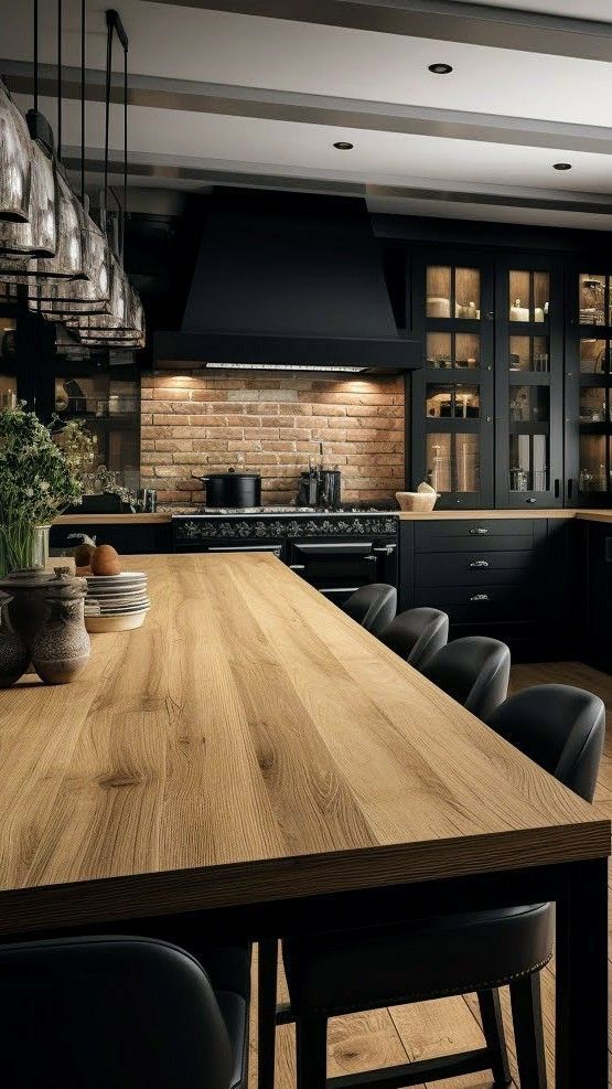 a large wooden table in a kitchen with black cabinets and stools next to it