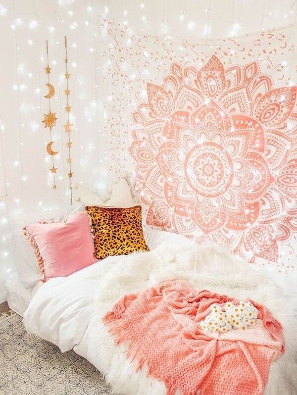 a bed with pink and white blankets on top of it next to a wall hanging