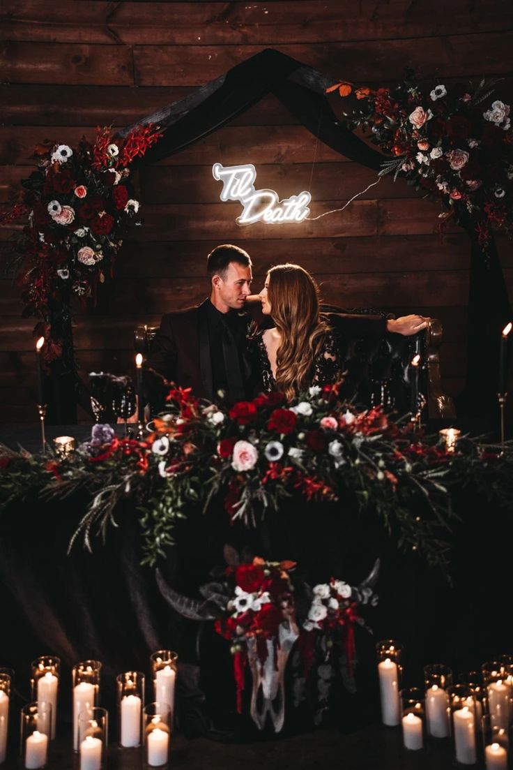 a man and woman sitting in front of a table with candles