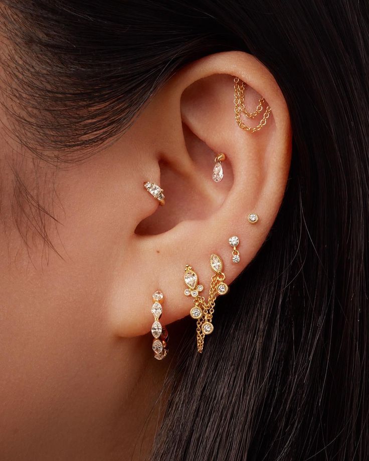 a close up of a woman's ear with three different types of piercings