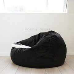 a black bean bag chair sitting on top of a hard wood floor next to a white wall