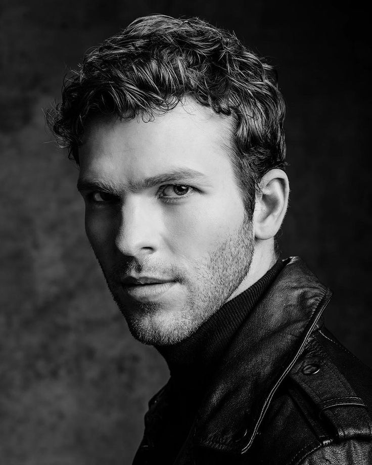 a black and white photo of a man in a leather jacket looking at the camera