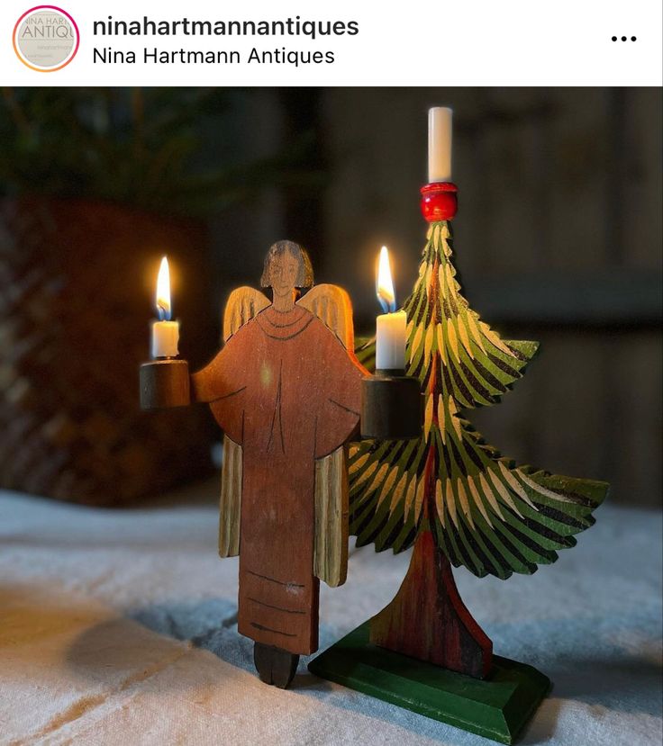 an angel figurine next to a lit christmas tree with two candles in it