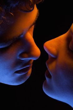 two people are looking into each other's eyes in front of a black background