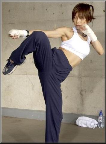 a woman in white shirt and blue pants doing a kickbox pose with one foot on the ground