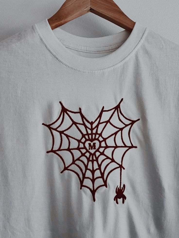 a white t - shirt with a spider web on it