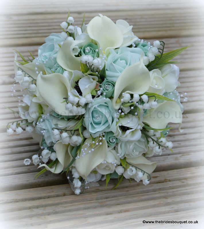 a bridal bouquet with white flowers and baby's breath on the top is sitting on a wooden surface