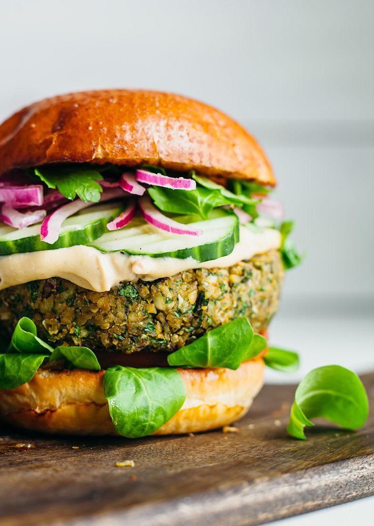 a close up of a sandwich on a cutting board with lettuce and onions