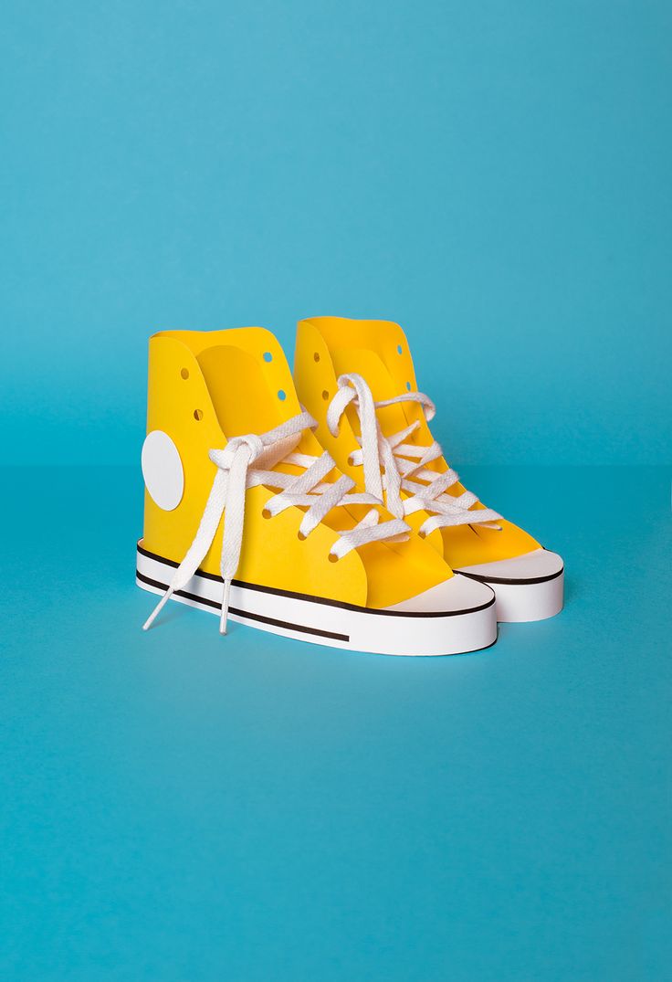 a pair of yellow sneakers with white laces on them sitting on a blue surface