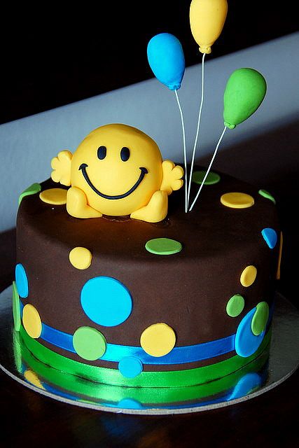 a smiley face cake with balloons on top