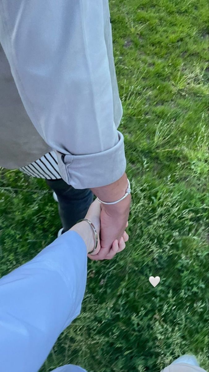 two people holding hands in the grass with hearts on their fingers and one person's leg