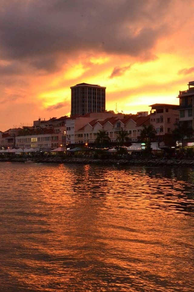 the sun is setting over some buildings and water