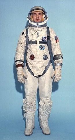 an astronaut is standing in front of a blue background with his hands on his hips