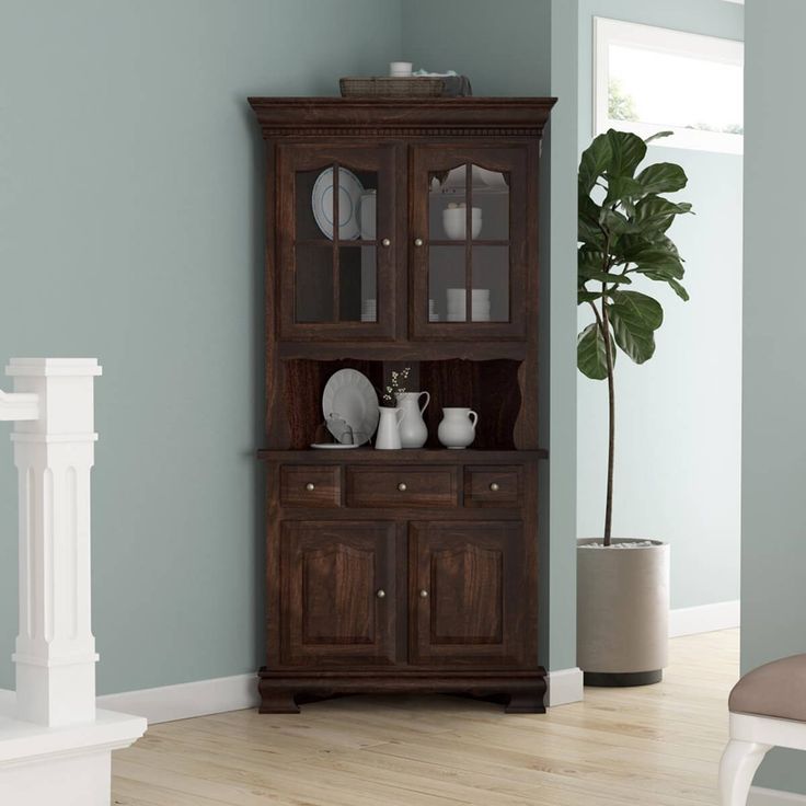 a wooden china cabinet with glass doors on the front and side, against a blue wall