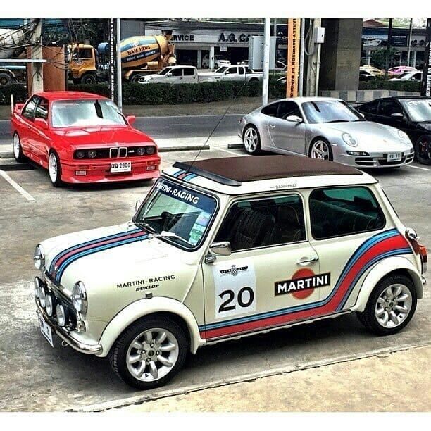 an old mini car is parked in a parking lot