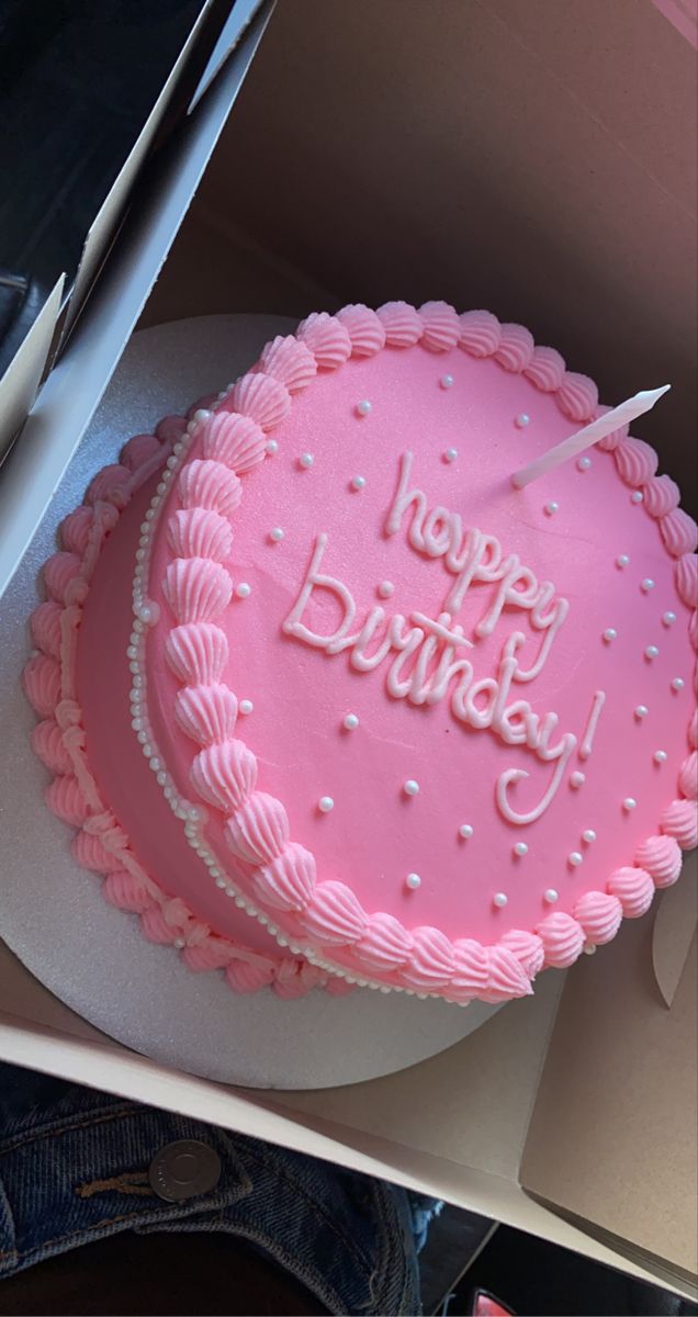 a pink birthday cake sitting on top of a white plate next to a pair of scissors