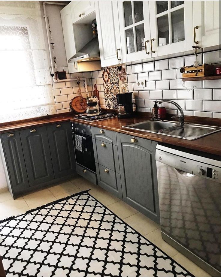 a kitchen with white cabinets and black counter tops, an area rug in front of the sink