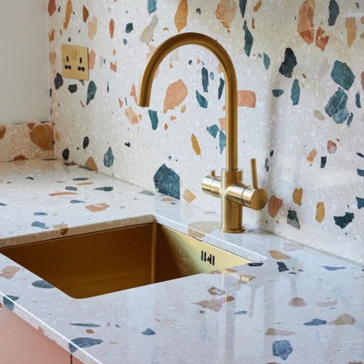 a kitchen counter with a sink and gold faucet