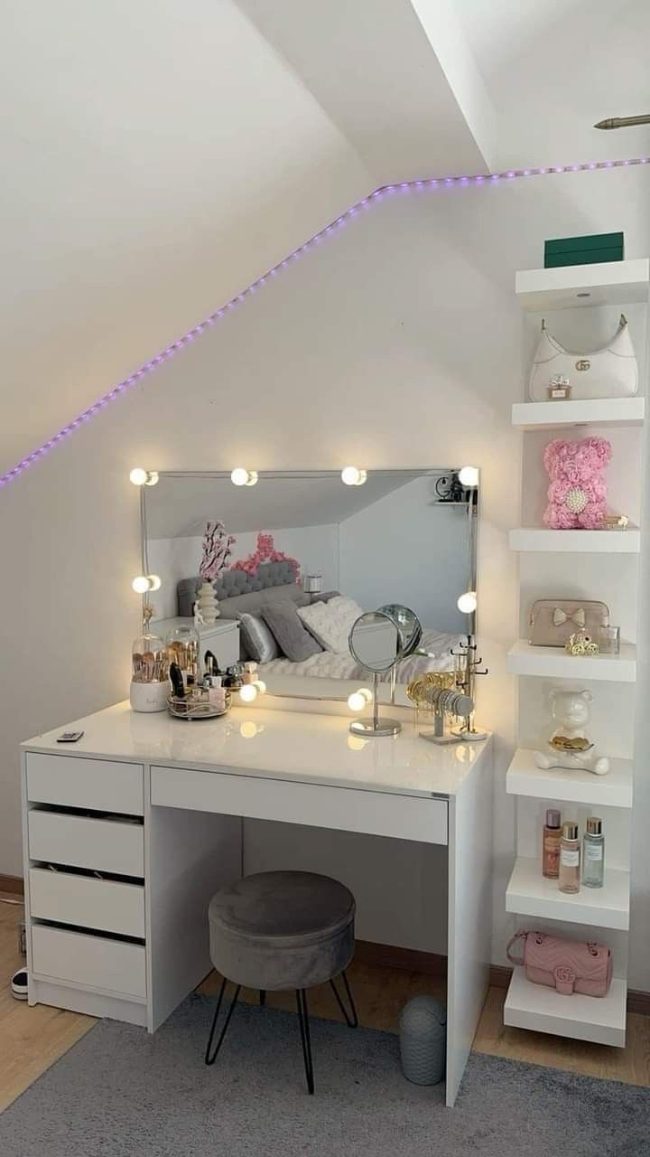 a white desk topped with a mirror next to a shelf filled with drawers and lights