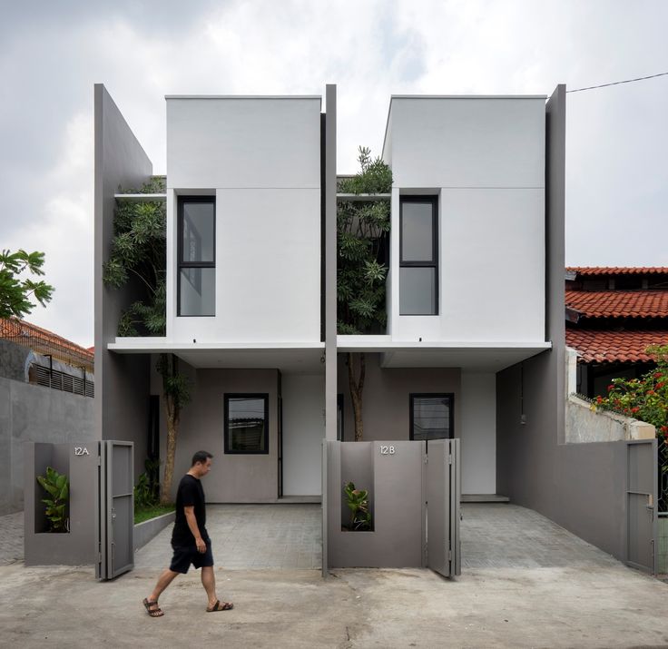 a man walking down the street in front of two buildings that are shaped like cubes