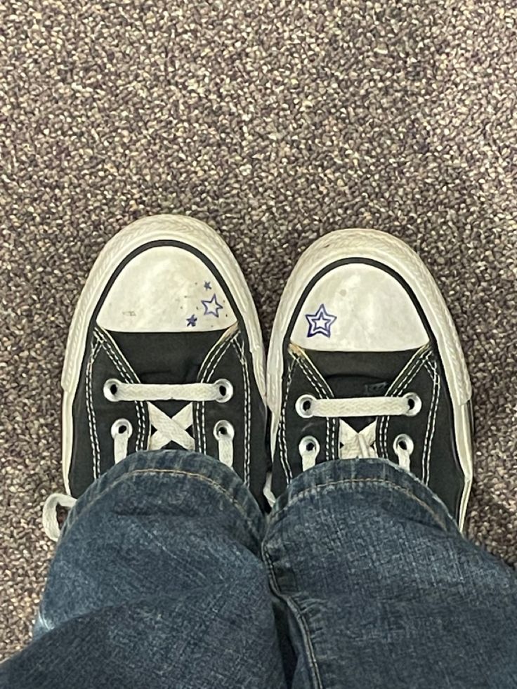 a person wearing black and white converse shoes