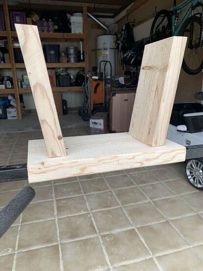 a wooden cart sitting on top of a tile floor next to a bike in a garage