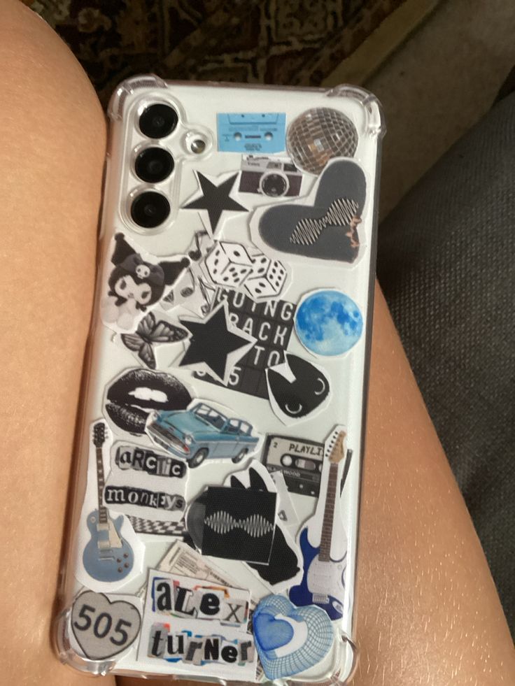 a person's arm with a cell phone covered in stickers on the back