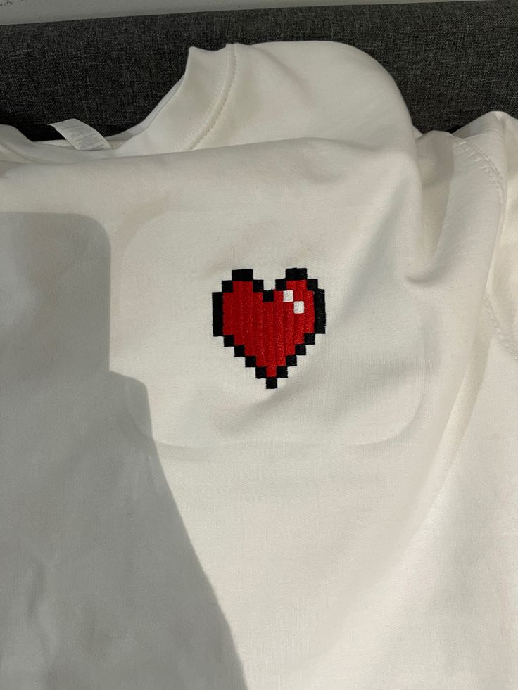 a white shirt with a red heart embroidered on it