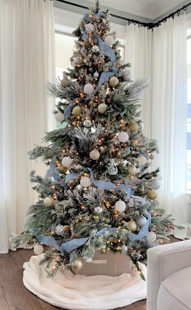 a decorated christmas tree in a living room with blue and silver ornaments on the top