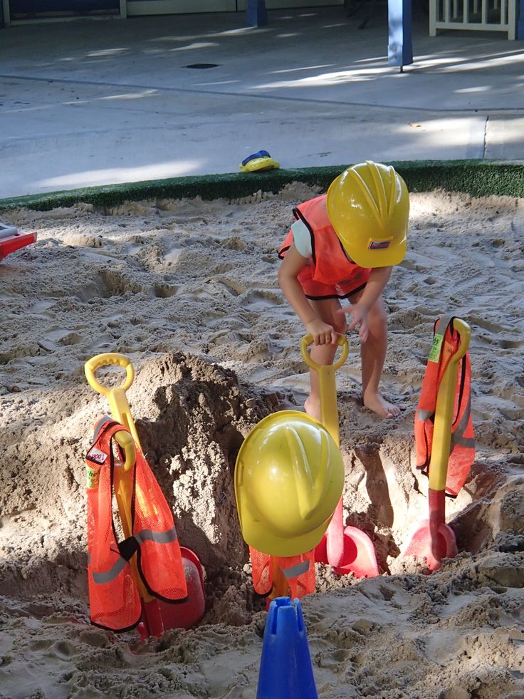 a little boy playing in the sand with some shovels and buoys on his head